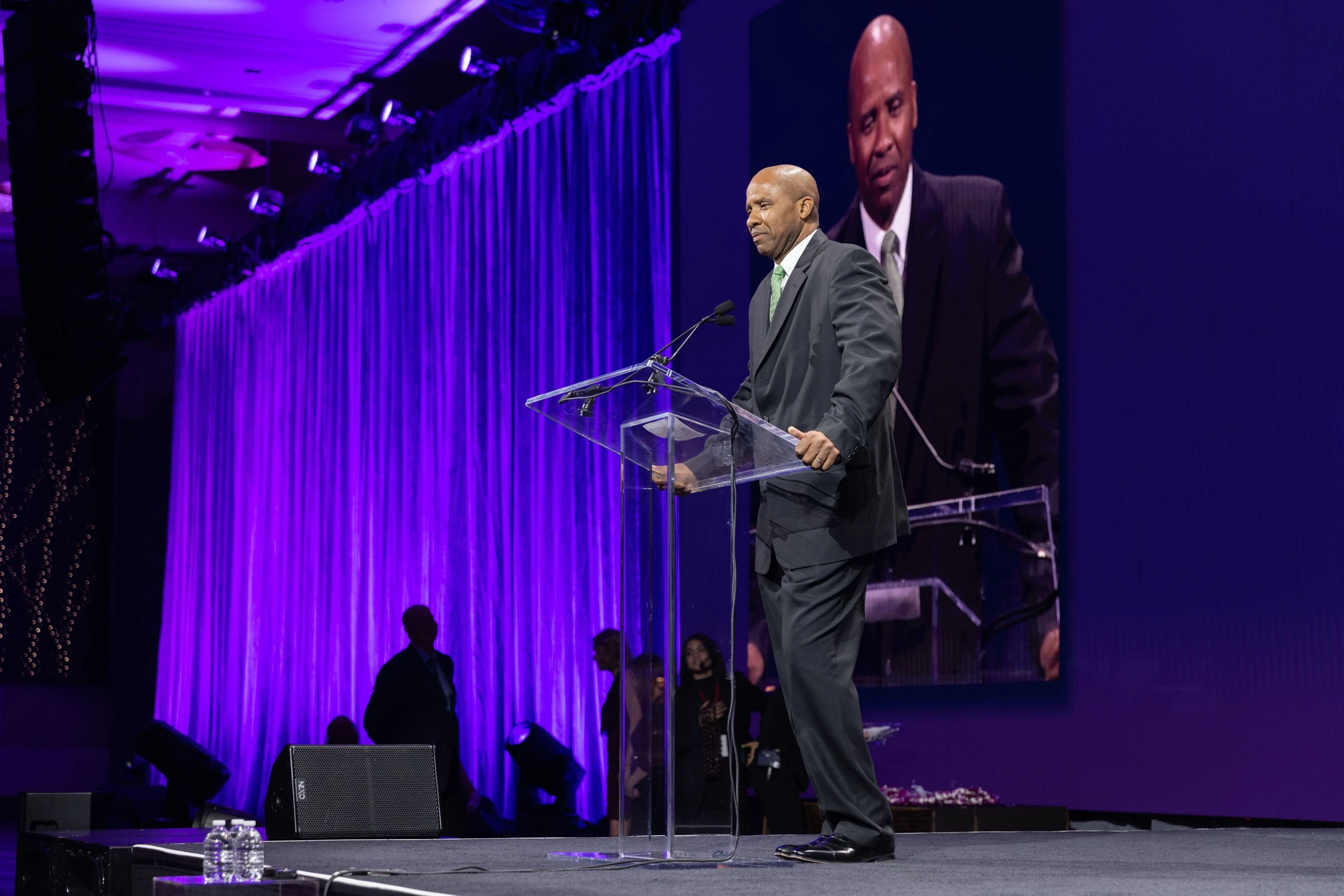 Rutherford delivering a keynote from a clear lectern